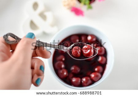 cherry compote placed in a white ceramic pot
White background  
Retro spoon
