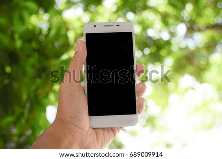 Hand holding smart phone on bokeh nature background