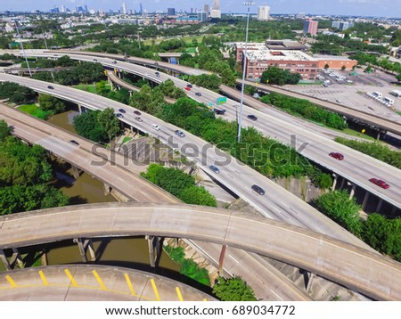 Aerial view highway I45 (Gulf Freeway), asphalt elevated road and Bayou River in downtown Houston, Texas, US. Passenger cars and trucks commuting daytime. Midtown office buildings are in the distance.
