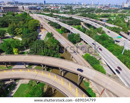 Aerial view highway I45 (Gulf Freeway), asphalt elevated road and Bayou River in downtown Houston, Texas, US. Passenger cars and trucks commuting daytime. Midtown office buildings are in the distance.