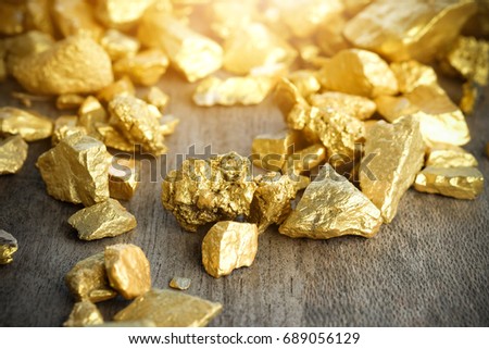 Close up lump of gold mine on wooden table Royalty-Free Stock Photo #689056129