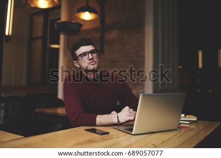 Thoughtful serious entrepreneur in spectacles thinking about improvements and growth for personal business project.Good looking freelancer pondering about new useful features in web application