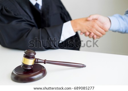 Gavel Justice hammer on wooden table with judge and client shaking hands after adviced in background at courtroom, lawyer service concept