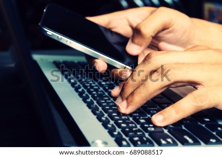 close up hand using smart phone and laptop computer on desk for business working, online social media, shopping online payment and searching data on website concept, vintage tone, selective focus