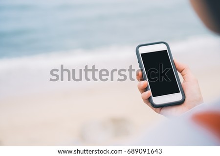 Copy space of woman hand using smart phone at beach abstract background. Travel adventure and business summer holiday concept. Shallow depth of field. Vintage tone filter effect color style.