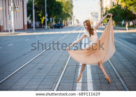 Ballerina in leotard and skirt and ballet shoes dancing on the street, jumps and bends