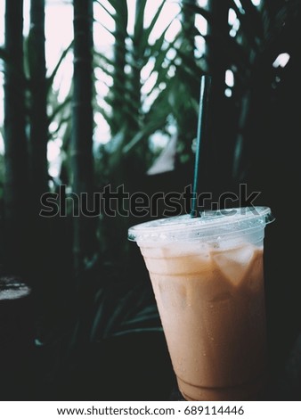 The picture of Thai iced tea in plastic cup on blur green tree background.  selective focus