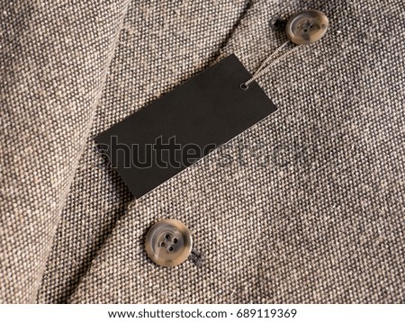 Blank black label price tag mockup on brown coat.