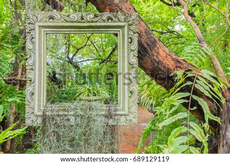 classic frame hanging on the tree in the garden .