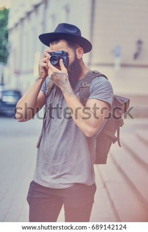 Portrait of casual tattooed, bearded street photographer taking pictures.