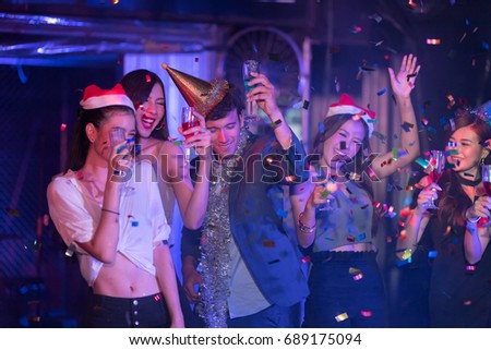 Motion blur movement of Cheerful Young people dancing and showered with confetti on a club party on Friday night hangout. Nightlife and people concept.