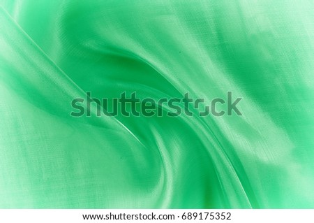 Background texture, pattern. Green silk background with some soft folds and highlights. green background abstract cloth or liquid wave illustration of wavy folds of silk texture satin 