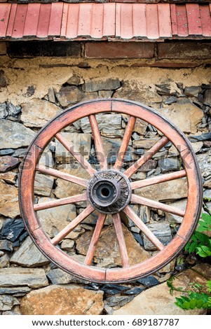 Antique wooden wheel from old cart hanging on the old stone wall as a decoration