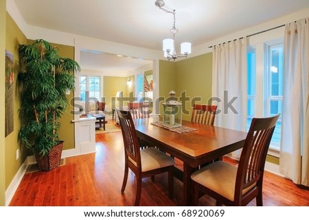 Green dining and living room with nice furniture and art.