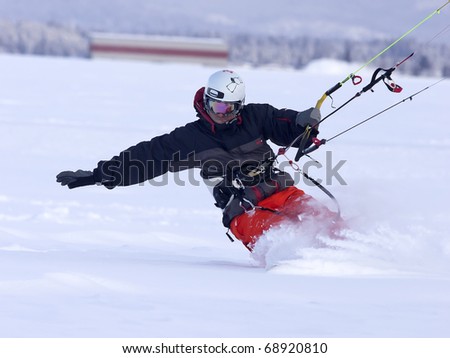 A man shreds snow on a snowboard while snow kiting. Royalty-Free Stock Photo #68920810