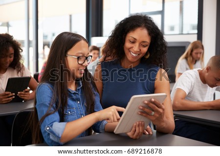 Teacher helping teenage schoolgirl with tablet computer Royalty-Free Stock Photo #689216878