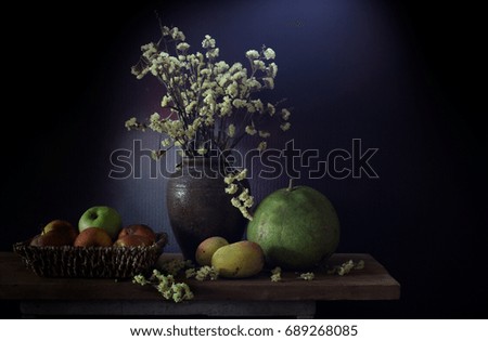 Still Life image of Dried flowers in the jar and fruits rotten in basket, All put on the wooden plank in dim light room / Selective focus

