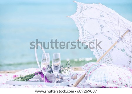 Picnic on the beach. Openwork umbrella, pillow, glasses, in the background a beautiful sea view. Very soft focus, pastel colors and light exposure are like an idea.
