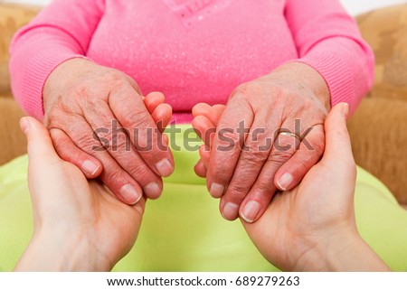 Photo of young caregiver holding elderly woman hands