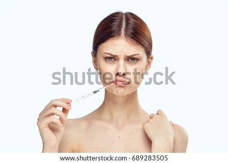 Young beautiful woman on white isolated background holds a syringe, plastic, medicine, surgery.