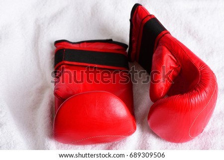 Pair of mittens for boxing in red color and traditional style on white towel background, top view. Concept of sportive equipment