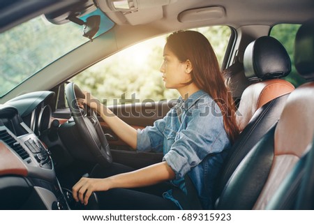 Beautiful Asian woman smiling and enjoying driving a car and hand is about to drive into gear on road for travel