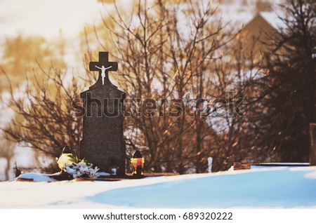 Grey cross on cemetery with candles and winter nature - funeral concept photo