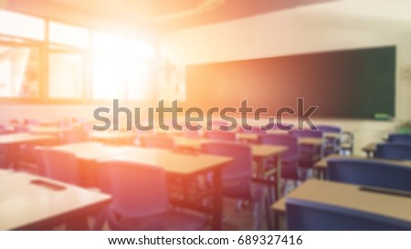 Back to school concept. Classroom in blur background without young student; Blurry view of elementary class room no kid or teacher with chairs and tables in campus. Royalty-Free Stock Photo #689327416