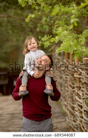 Portrait of a father and daughter standing and laughing in the summer garden, happy family
