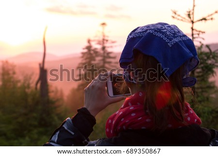 A young girl takes photos of nature on the phone