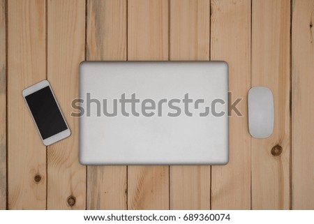 Top view flat layout of laptop computer close, mouse and smartphone On wood top.