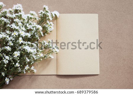 blank open notebook or diary made by craft paper with white flower bouquet.