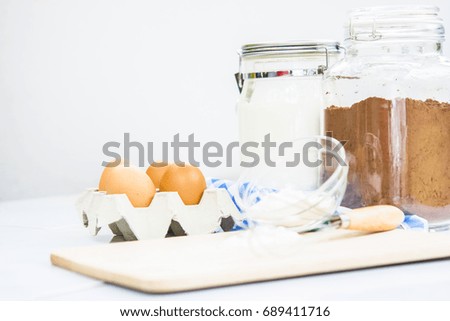 Cocoa Powder with Wheat Flour and Eggs with Bakery Equipment on chopping board.
