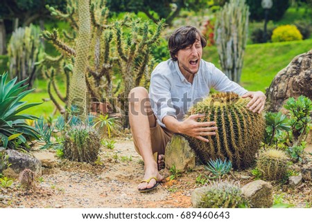 A man is sitting among large cacti. Pain concept.