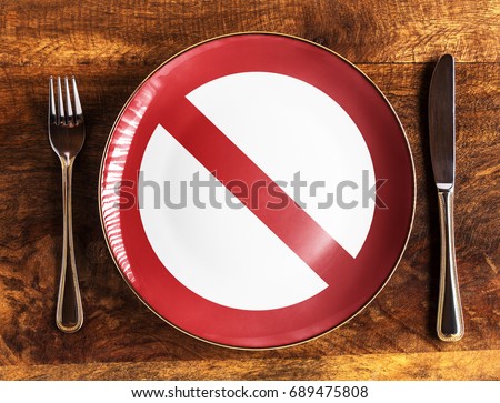 No food concept with forbidden symbol on plate with fork and knife on wooden table, overhead view Royalty-Free Stock Photo #689475808