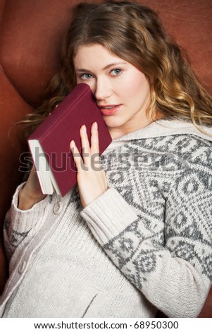 young woman reads a book lying on a couch