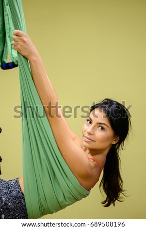 Young girl do fly yoga and stretches on yellow background