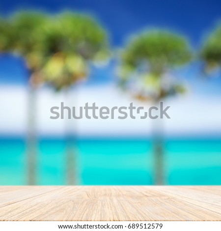 Wood plank with blurred sea and sugar palm tree background. Concept of beach in summer.