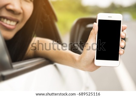 Women was sitting in the car.She was show smart phones. The mobile has a black space for your pictures and text.road trip, travel, destination technology and people concept.