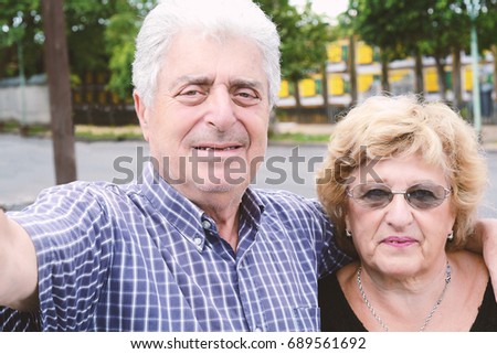 Portrait of an elderly couple taking selfie outdoors.