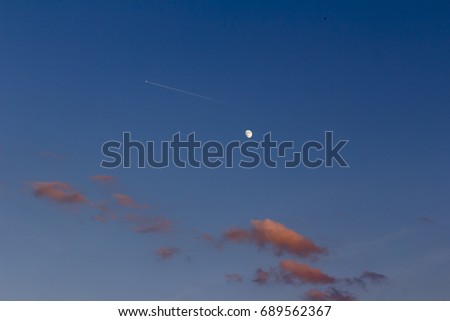 moon and airplane on evening blue sky with clouds, awaiting vacation trip