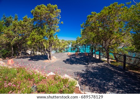 Coastline promenade with pine trees and tourquise clear water at Porto Cervo town. Porto Cervo is capital of Costa Smeralda, Sardinia, Italy.
