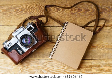 Old retro camera,  spiral blank kraft paper tablet on vintage rustic wooden planks boards. Education photography courses back to  school concept abstract background. Close up, top view, copy space.