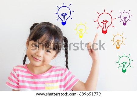asian child point upper and smile happily on white background with some colorful picture of the electric bulbs ,mean that she got some ideas