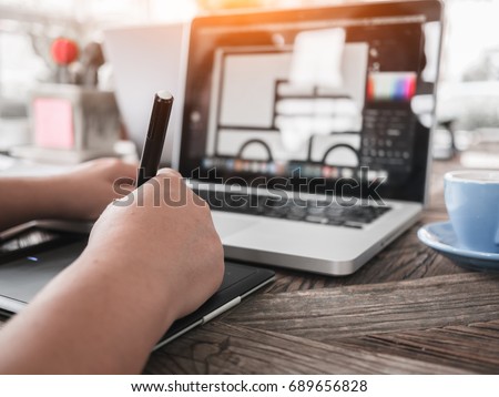 Freelance Photo editor, Artist, Graphic Designer working at desk in creative office. Artist drawing something on graphic tablet at the office.

