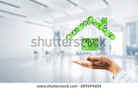 Hand of businessman showing house or home gear sign in palm