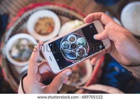 Closeup Asian woman use smart phone to take pictures of Thai food before eating.