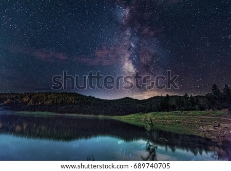 The Milky Way, full of stars, lights up the night sky and reflects in a small fishing lake in the mountains outside of Ruidoso, New Mexico