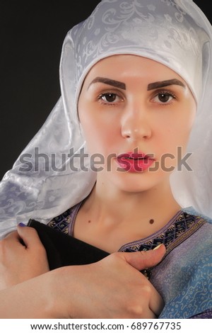 Image of Muslim girl is holding qoran. Vertical portrait of a beautiful muslim girl. In the hands of a girl Koran