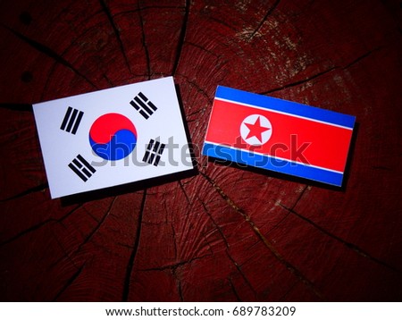 North Korean flag with South Korean flag on a tree stump isolated